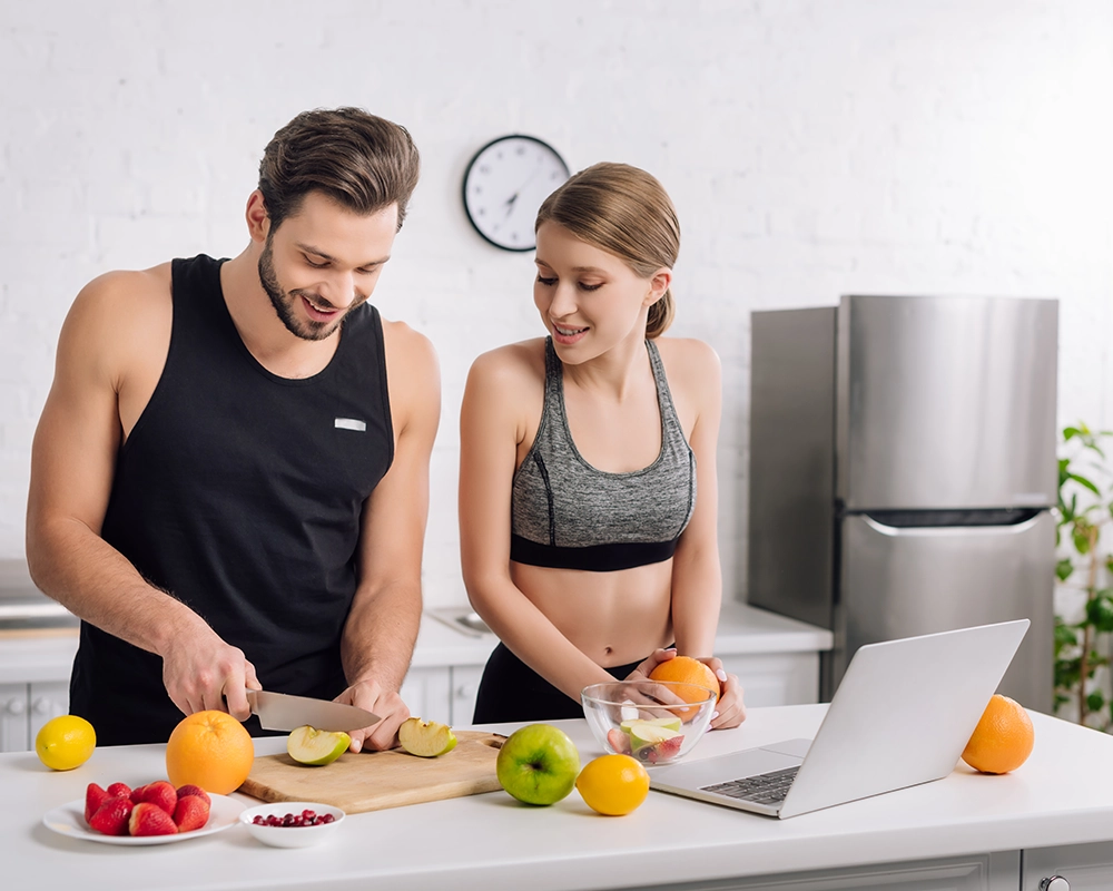 Pareja cortando fruta en la cocina.